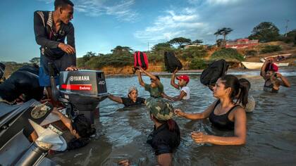 Un grupo de migrantes venezolanos aborda un bote que los llevará hasta la isla de Curaçao