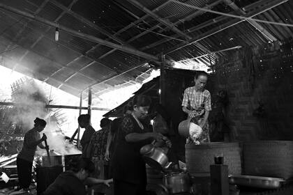 Un grupo de mujeres cocinan para los asistentes en el ritual funerario o la ceremonia de Rambu Solo en honor a Ne Siang en la aldea de Bua Tallulolo.