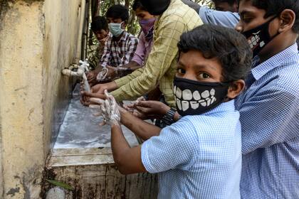 Un grupo de niños se la va las manos en un lugar público en la India