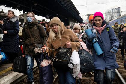 Un grupo de personas corre por las vías para llegar al próximo tren que se dirige al oeste hacia Lviv, en la estación principal de trenes en Kiev, el 4 de marzo de 2022