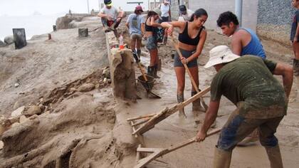 Un grupo de personas despejan el lodo después de una inundación relacionada a los efectos de El Niño en la costa de Perú