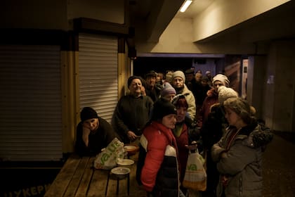 Un grupo de personas espera en fila para recibir comida en una estación de metro utilizada como refugio antibombas, mientras continúan los ataques rusos sobre Járkiv, Ucrania, el 25 de marzo de 2022