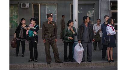 Un grupo de personas esperan un autobús durante la hora pico de la mañana en Pyongyang