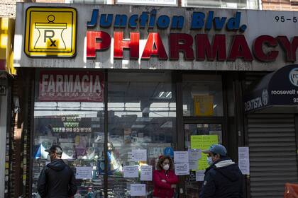 Un grupo de personas hace fila en la puerta de una farmacia, en Queens