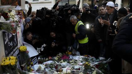 Un grupo de personas presta homenaje a las víctimas del atentado que mató 12 trabajadores de Charlie Hebdo en 2015