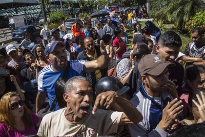 Un grupo de personas reclama que abran las puertas de un supermercado, en Caracas