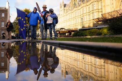 Un grupo de personas se manifiesta frente al Parlamento británica tras la renuncia de la primera ministra Liz Truss, en Londres, el jueves 20 de octubre de 2022. (AP Foto/Alberto Pezzali)