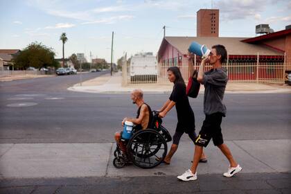 Un grupo de personas sin hogar, se dirigen hacia un mercado en medio de la peor ola de calor registrada en la ciudad el 24 de julio de 2023 en Phoenix, Arizona.