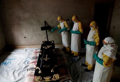 Un grupo de trabajadores sanitarios desinfectan un a tumba