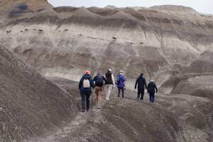 Un grupo de turistas comienza la caminata en el Bosque Petrificado La Leona, rodeado de las formaciones montañosas conocidas como Badlands