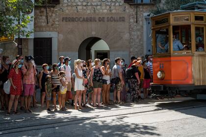 Un grupo de turistas con mascarilla espera el tranvía que se dirige a Sóller, Mallorca, una de las ciudades afectadas por el repunte de casos de coronavirus. 