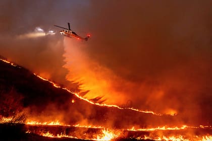 Un helicóptero arroja agua sobre las llamas en West Hills, Los Ángeles, el 9 de enero de 2025. (AP Foto/Ethan Swope)