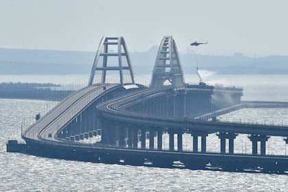 Un helicóptero arroja agua sobre un puente para sofocar un incendio, en el puente que conecta la península de Crimea con el territorio continental ruso sobre el estrecho de Kerch, en Kerch, el 8 de octubre de 2022. (AP Foto)