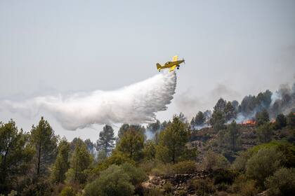 Un helicóptero de extinción de incendios arroja agua sobre las llamas durante un incendio forestal, Barcelona, España, el 18 de julio de 2022