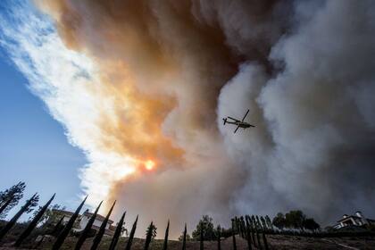 Un helicóptero lanza agua para extinguir los incendios forestales en Paradise