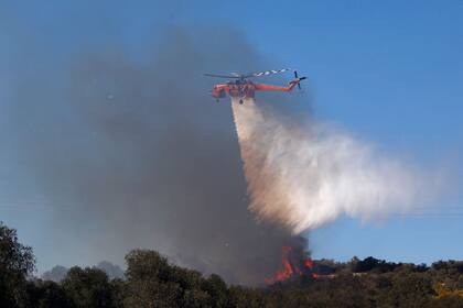Un helicóptero rocía agua en un intento de extinguir un incendio forestal que estalló en Kitsi, un suburbio del sur de Atenas, el 19 de junio de 2024.