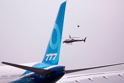 Un helicóptero sigue al avión Boeing 777X antes de su vuelo inaugural en Paine Field en Everett