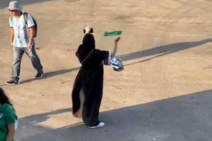 Un hincha de la Argentina pasa cabizbajo a metros de la mujer de Arabia Saudita que festeja en soledad el triunfo de su seleccionado