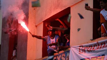 Un hincha enciende una bengala desde un balcon de un edificio para ver a los equipos de fútbol "La Pólvora" (Pólvora) y "Los chatarreros" (El Scrappers) jugar la semi-final de la Copa del Porvenir campeonato de fútbol callejero en Lima, Perú