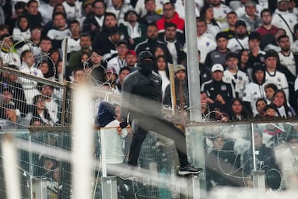 Un hincha trepa en un panel de cristal durante un partido de la Copa Libertadores entre Colo Colo de Chile y Fortaleza de Brasil en Santiago, el jueves 10 de abril de 2025 (AP Foto/Esteban Félix)