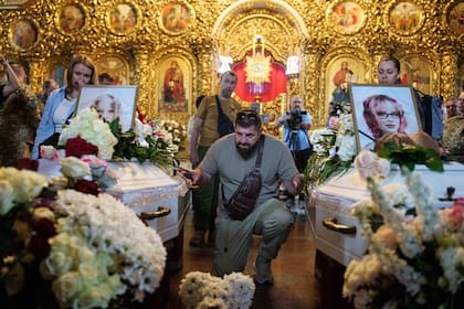 Un hombre al lado de los ataúdes de niñas muertas en un ataque ruso, en Kiev, Ucrania, el 19 de mayo del 2026. (AP foto/Evgeniy Maloletka)