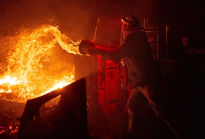 Un hombre arroja agua sobre las llamas del incendio en California (Archivo/ AP Foto/Ethan Swope)