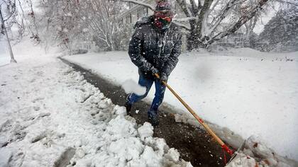 Un hombre barre nieve de la vereda en New Bedford, Massachusetts