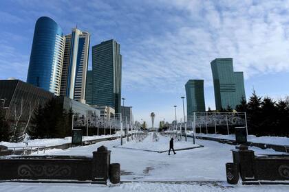 Un hombre camina en el centro de Astana, la excapital de Kazajistán con el monumento de Bayterek al fondo