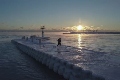 Un hombre camina en un muelle congelado durante el amanecer en medio de las frías temperaturas causadas por el vórtice polar, una corriente de aire que gira alrededor del Polo Norte. el 29 de enero, en Chicago.
