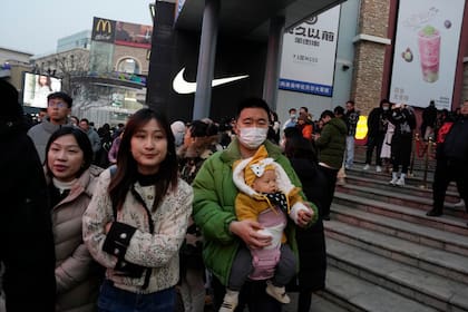 Un hombre carga a un bebé en un centro comercial, el 30 de diciembre de 2023, en Beijing. (AP Foto/Ng Han Guan)