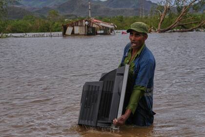 Un hombre carga con un televisor que sacó de su casa, anegada tras el paso del huracán Melissa, en Santiago de Cuba, el 29 de octubre de 2025 (AP Foto/Ramón Espinosa)