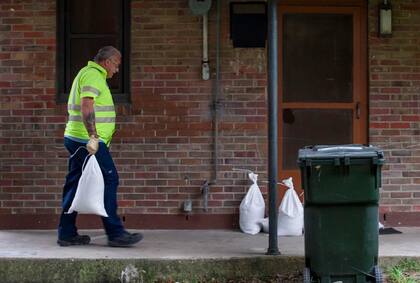 Un hombre carga sacos de arena hasta la puerta principal de una vivienda en Charleston, Carolina del Sur, este jueves 29 de septiembre de 2022 (The Post and Courier/Henry Taylor)