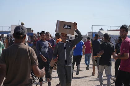Un hombre carga una caja de ayuda humanitaria distribuida por la polémica fundación GHF