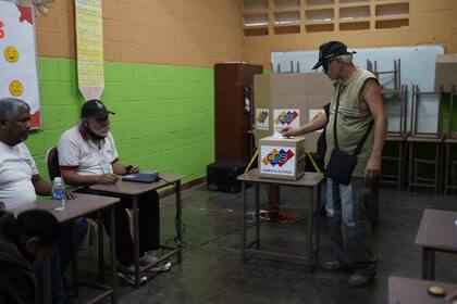 Un hombre coloca su recibo de votación electrónica en una urna durante un referéndum sobre el futuro de un territorio en disputa con Guyana, en un colegio electoral en Caracas, Venezuela, el domingo 3 de diciembre de 2023