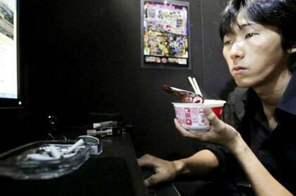 Un hombre come frente a la pantalla de una computadora en uno de los cibercafés