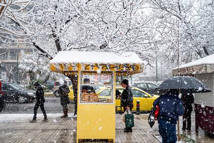 Un hombre compra pan en un pequeño puesto durante la nevada en Atenas, Grecia