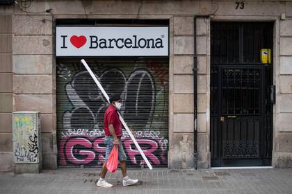 Un hombre con mascarilla pasa frente a una tienda cerrada en el centro de Barcelona el 12 de agosto de 2020
