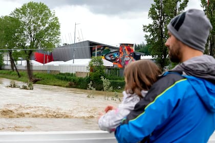 Un hombre con un niño en brazos contempla la crecida del río Santerno, y en el fondo de ve el circuito Enzo e Dino Ferrari en Imola
