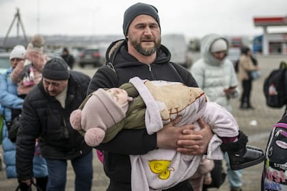 Un hombre con un niño en brazos en el paso fronterizo de Porubne, a 5 de marzo de 2022, en el oeste de Ucrania