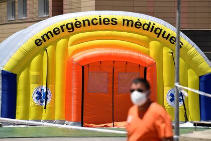 Un hombre con una máscara facial pasa frente a un hospital de campaña establecido para casos de coronavirus fuera del Hospital Universitario Arnau de Vilanova en Lleida el 4 de julio de 2020