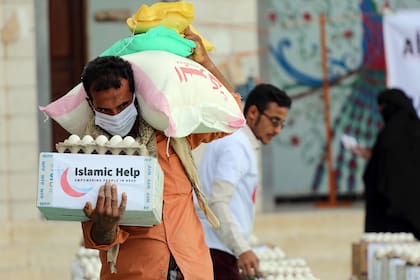 Un hombre con una máscara protectora recibe ayuda humanitaria en la tercera ciudad de Taez en Yemen, el 8 de mayo de 2020, en medio de la pandemia de coronavirus