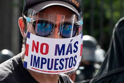 Un hombre con una máscara que dice "No más impuestos" participa en una protesta contra la moción del gobierno de aumentar los impuestos para llegar a un acuerdo crediticio con el FMI, frente a la casa presidencial en San José, en octubre 12, 2020