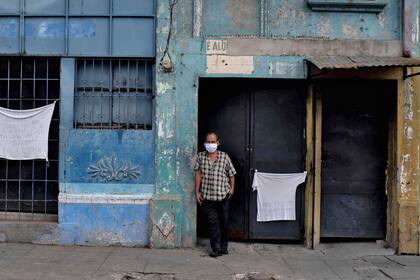 Un hombre con una remera blanca en la puerta de su casa en El Salvador, reclama ayuda humanitaria