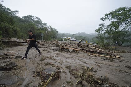 Un hombre cruza una carretera bloqueada por un deslizamiento de tierra provocado por el huracán Otis cerca de Acapulco, México, miércoles 25 de octubre de 2023. (AP Photo/Marco Ugarte)
