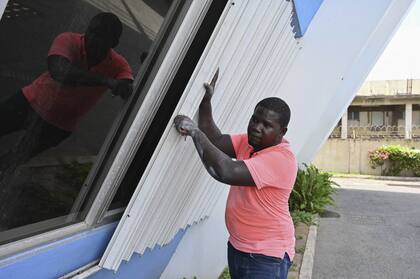 Un hombre cubre las ventanas de un edificio para protegerlo del huracán Beryl que se aproxima en Kingston, Jamaica, el martes 2 de julio de 2024.