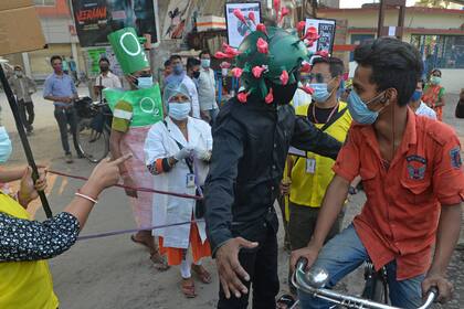 Un hombre de una organización no gubernamental (ONG) con un atuendo que se asemeja al coronavirus se mueve por un mercado instando a las personas a seguir los protocolos de seguridad durante una campaña de sensibilización celebrada en Siliguri el 25 de abril de 2021