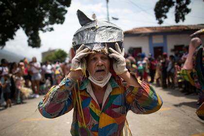 Un hombre disfrazado de diablo se arrastra de rodillas hacia una iglesia mientras paga una penitencia como parte de las celebraciones de la festividad católica del Corpus Christi en Naiguata, Venezuela