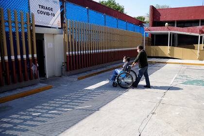 Un hombre empuja a un pariente en una silla de ruedas en el área reservada para la Covid-19 del Hospital General en la Ciudad de México el 5 de mayo de 2020