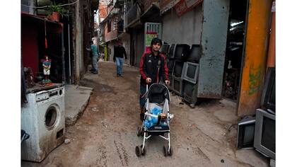 Un hombre empuja un cochecito con un perro a lo largo de una calle de la Villa 31 en Buenos Aires, Argentina