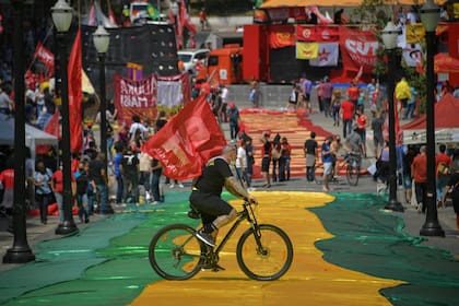 Un hombre en bicicleta pasa por una carretera cubierta con la bandera brasileña durante una manifestación contra el presidente brasileño Jair Bolsonario en Sao Paulo